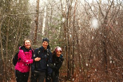 Portrait of friends in forest during snowy weather