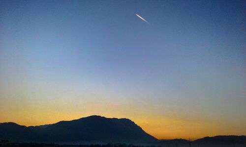 Scenic view of silhouette mountains against clear sky during sunset