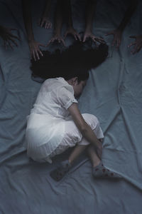 Cropped hands reaching towards girl while sleeping on bed in darkroom