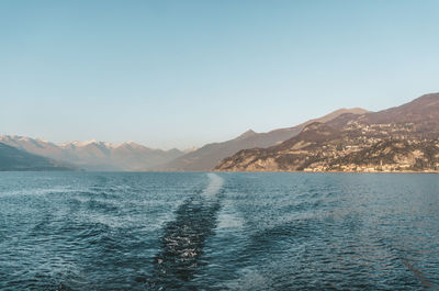 Scenic view of sea and mountains against clear blue sky