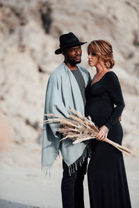 Rear view of man with woman standing on beach