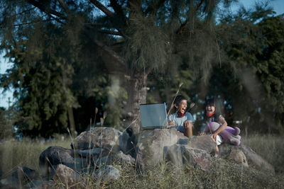 People sitting on field by trees