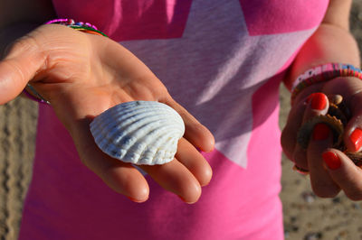 Close-up of baby girl holding seashell on beach