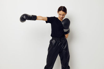 Side view of man exercising with dumbbells against white background