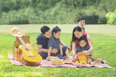 Happy family taking selfie while sitting on picnic blanket at park