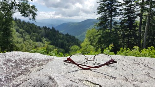 Close-up of sunglasses on mountain against sky