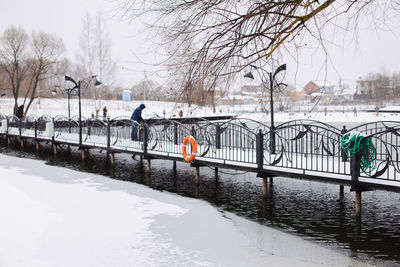 People on frozen river in city during winter