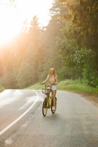 A cheerful young woman enjoys a bike ride on a sunny country outdoor getaway person