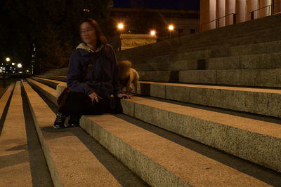 Full length of woman sitting on staircase at night