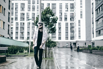 Young man smoking while walking on wet sidewalk