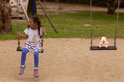 Full length of woman sitting on swing at playground