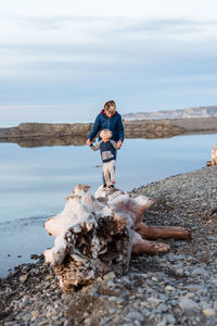 Older brother helping younger brother walk on log near water