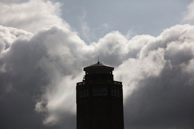 Low angle view of lighthouse by building against sky