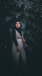 Portrait of woman standing by tree during winter