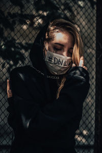 Woman with covered mouth standing outdoors