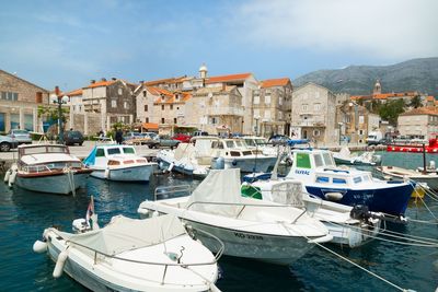 Boats moored in sea by city against sky