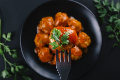 Closeup of a homemade meatball seasoned with parsley and sauce