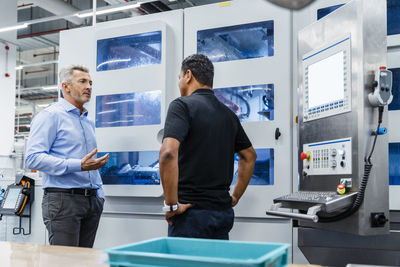 Businessman explaining engineer by machine in industry