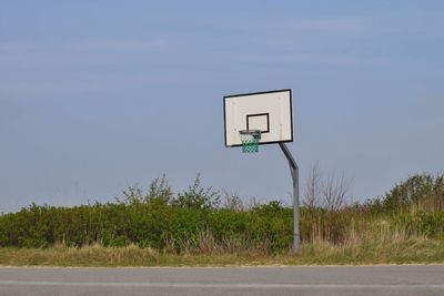 Basketball hoop on field against sky