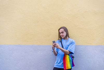 Man using mobile phone while wearing a belt bag with the lgbt rainbow flag.