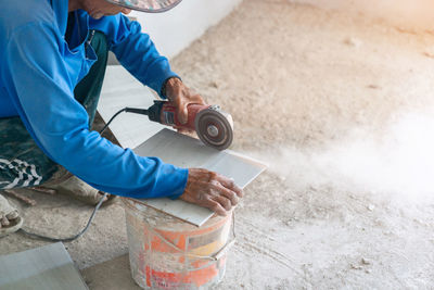 Construction worker cutting floor tiles forbuilding using an electric grinding..