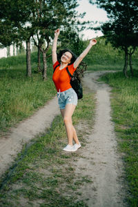 Full length of woman with arms raised on field