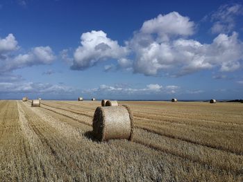 Hay bales on field against sky