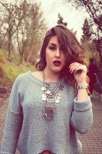 Portrait of beautiful woman walking on footpath against trees