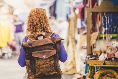 Rear view of woman with backpack standing at market