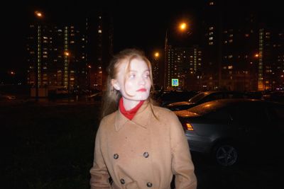 Portrait of young woman standing in city at night