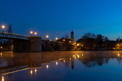 Illuminated bridge over river against sky at night