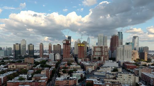 Aerial view of buildings in city against cloudy sky