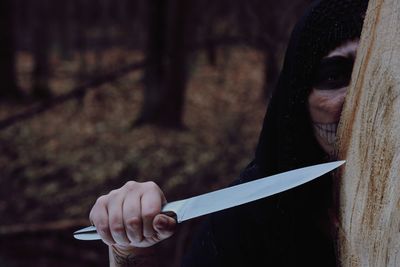 Girl wearing skull mask while holding knife during halloween