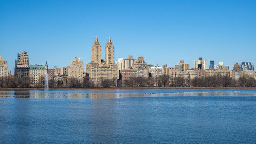 River by buildings against blue sky