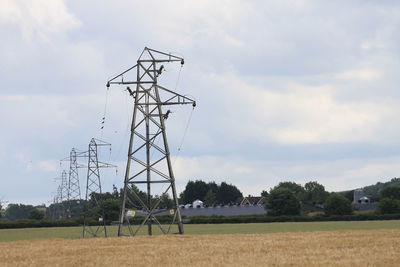 Electricity pylon on field against sky