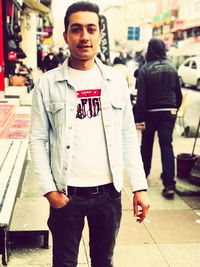 Portrait of young man standing on street in city