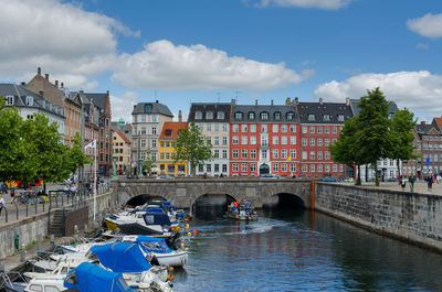 Bridge over canal amidst buildings in city against sky