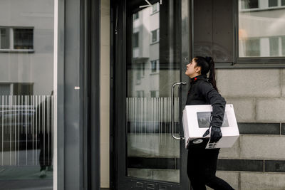 Young delivery woman delivering package at building