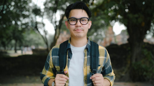 Portrait of young man standing against plants