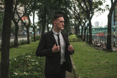 Young man standing against trees