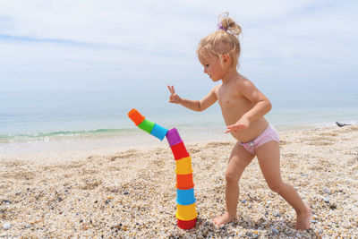 Playful girl at beach against sky