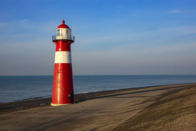 Lighthouse by sea against sky