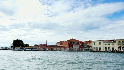 Buildings by river against sky