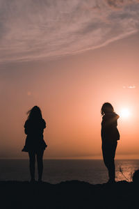 Silhouette woman standing on beach against sky during sunset