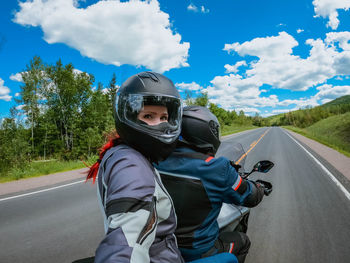 Motorcycle passenger woman in a helmet makes selfie on action camera while riding on motorcycle 
