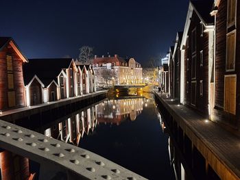 Bridge over river amidst illuminated buildings in city at night