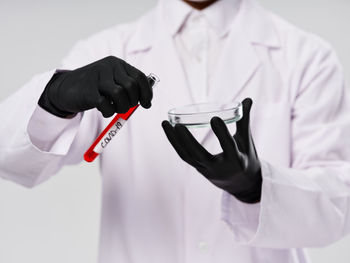 Midsection of doctor holding stethoscope against white background