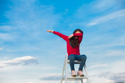 Rear view of woman sitting against sky