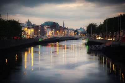 Illuminated bridge over river against sky in city
