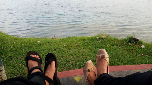 Low section of woman on grass by water